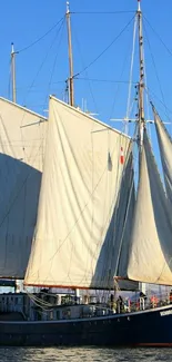 Majestic sailing ship against a vibrant blue sky, gliding over calm waters.