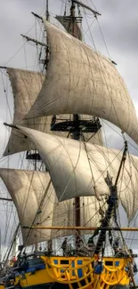 Majestic sailing ship with full sails on a cloudy ocean day.