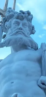 Majestic marble statue of Neptune under a blue sky.