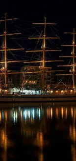 Majestic tall ship illuminated at night in a tranquil harbor.