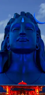 Blue Shiva statue with serene sky background for mobile wallpaper.