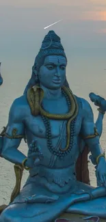 Blue Shiva statue with seashell backdrop at sunset, exuding divine serenity.