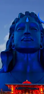 Majestic blue Shiva statue with serene expression and vibrant sky.