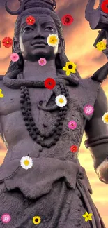 Shiva statue with colorful flowers at sunset, perfect for mobile wallpaper.