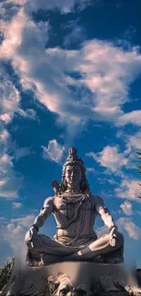 Majestic Shiva statue under blue and cloudy sky.