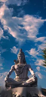 Statue of Shiva against a blue sky with clouds.