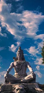 Shiva statue under a vibrant blue sky with clouds and greenery.