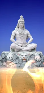 Majestic Shiva statue against a vibrant blue sky in a serene desert landscape.