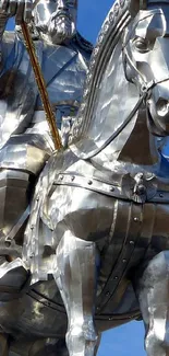 Metallic statue of a rider on horseback against a blue sky.