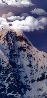 Snow-capped mountain peak with clouds against a vivid blue sky.