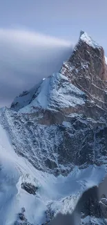 Snowy mountain peak under cloudy sky.