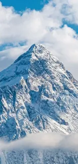 Majestic snowy mountain peak against blue sky and clouds.