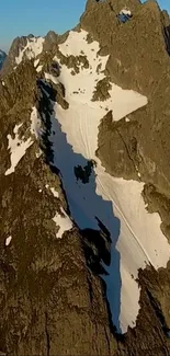 Snowy mountain peaks at sunset with brown rocky formations.