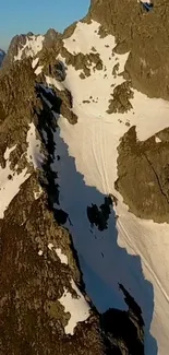 Snow-capped mountain peaks under blue sky in rugged terrain.