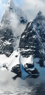 Majestic snowy mountain reflected in water under a cloudy sky.