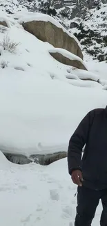 Smiling person standing in snowy mountain landscape.