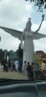 Angel statue in a busy park setting with people around.