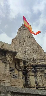 Majestic stone temple with colorful flags under a cloudy sky.