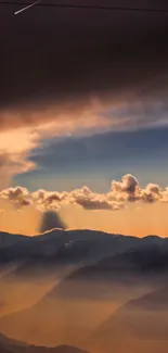 Sunset view of mountains with clouds casting a golden hue over the landscape.