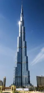 Majestic skyscraper under a clear blue sky with urban skyline in view.