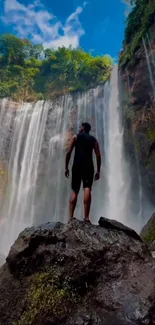 Adventurer standing before a majestic waterfall surrounded by lush greenery.