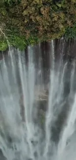 Aerial view of a majestic waterfall surrounded by lush green forest.