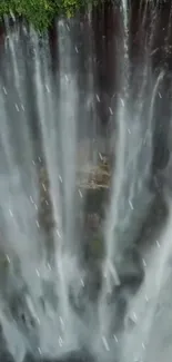 Aerial view of a dramatic waterfall surrounded by lush greenery.