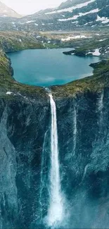 Majestic waterfall flowing into lake surrounded by mountains.