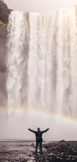 Majestic waterfall with a rainbow in misty background.