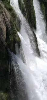 Majestic waterfall cascading down rocky terrain with lush greenery.