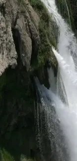 Majestic waterfall flowing over a rocky cliff with lush greenery.