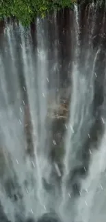 Aerial view of a misty waterfall cascading down lush cliffs.