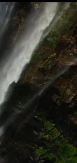 Stunning mobile wallpaper of a waterfall cascading down a rugged, lush mountain.