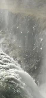 Majestic waterfall over rocky cliffs with mist and waves.