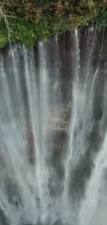 Aerial view of a majestic waterfall cascading over lush green cliffs.