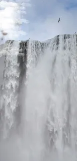 Majestic waterfall cascading down, surrounded by clouds.