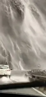 Car driving beside a majestic waterfall cascading down rocky cliffs.