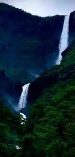 Majestic waterfall amid lush green mountains creating a serene view.