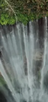 Aerial view of a majestic waterfall with lush greenery surrounding it.