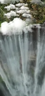 Majestic waterfall with lush greenery and clouds.