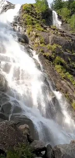 Majestic waterfall cascading down rocky cliffs with lush green surroundings.