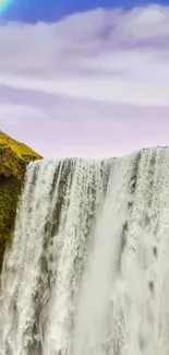 Waterfall with rainbow under a blue sky.