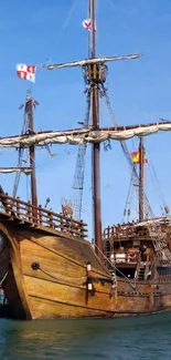 A majestic wooden ship sailing on the ocean under a clear blue sky.