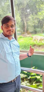 Man standing by glass, white tiger in background.