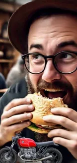 Bearded man enjoys burger near a vintage red motorcycle in a cafe setting.