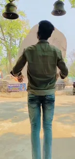 Man enjoying outdoor scene under bell in park.