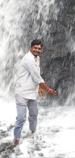 Man joyfully standing under a waterfall.