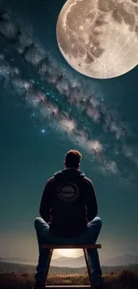 Man sitting and gazing at a full moon under a stunning night sky.