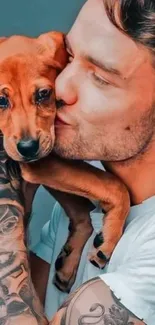 Man with tattoos hugging a brown puppy lovingly.