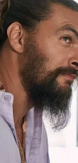 Portrait of a bearded man wearing a lilac shirt with a topknot.